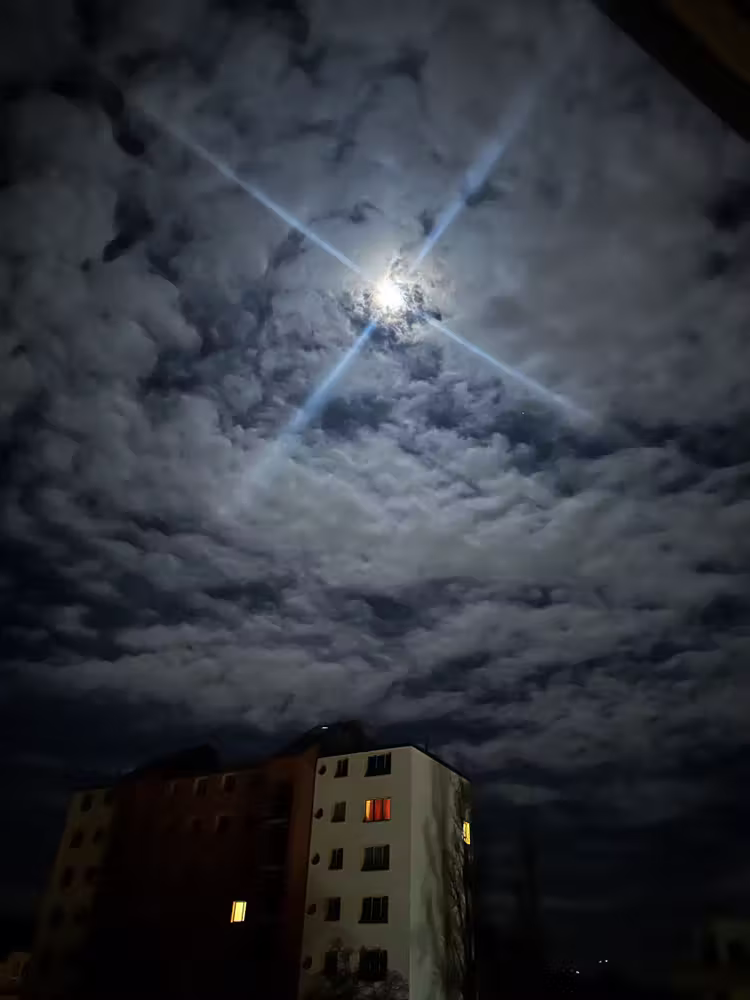 Moon breaking through the clouds over an apartment block