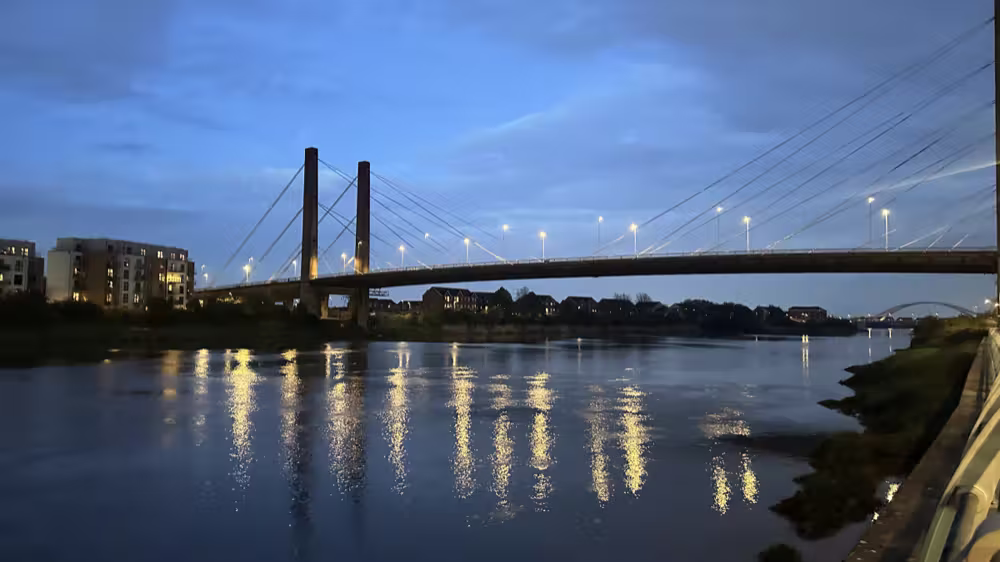 Bridge lights reflected in the river at dusk