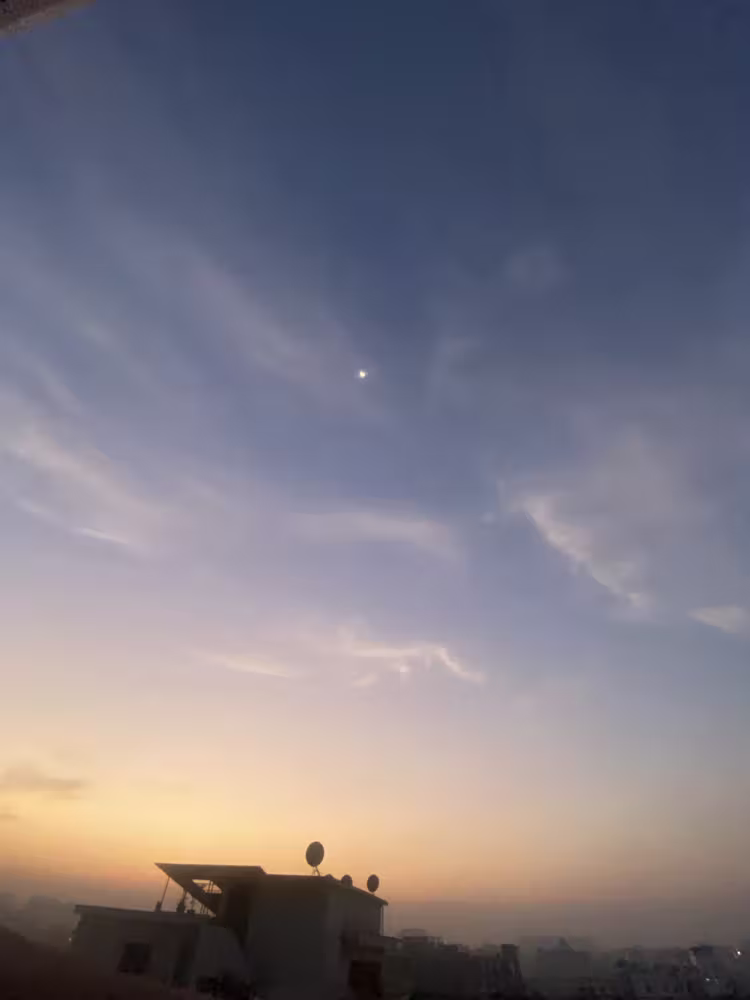 Moon in the dusk sky above the rooftops