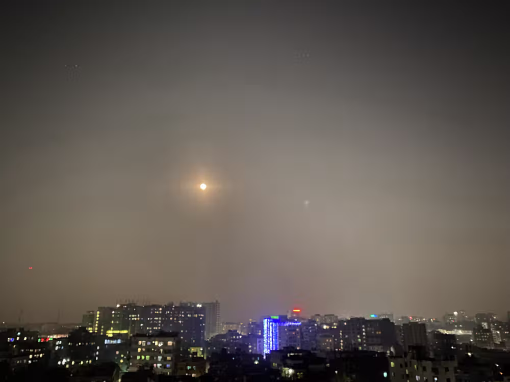 Moon over the city lights on a hazy night