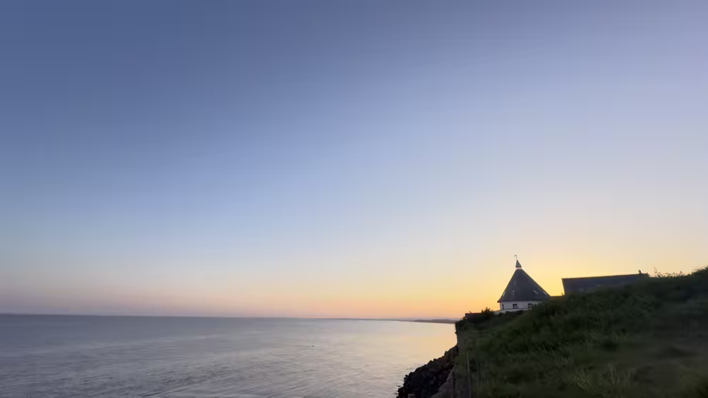Sunset over the sea by a small lighthouse