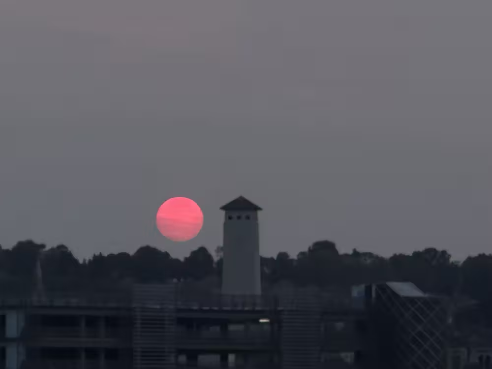 Red sun through the haze behind a tower