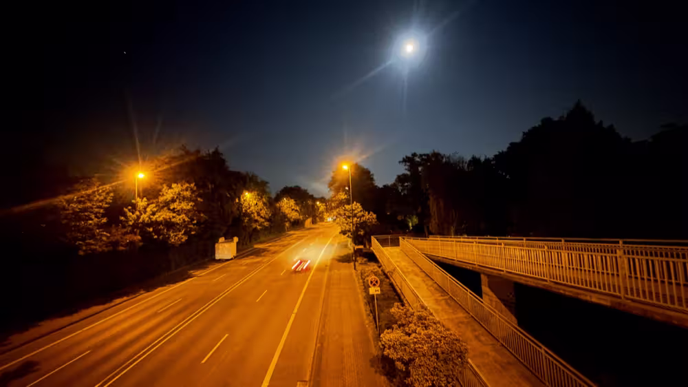 Moon over a road lit orange at night